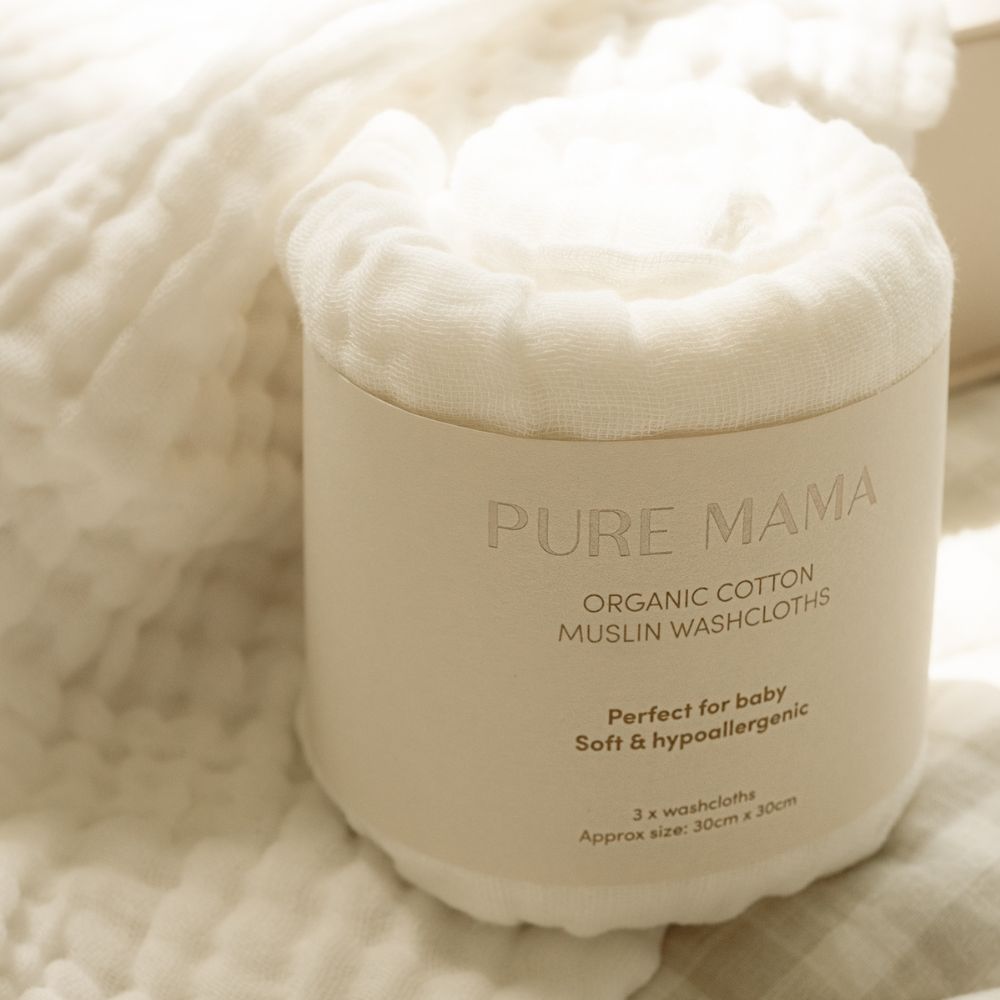 A rolled-up white Cotton Muslin Set by Pure Mama NZ rests on a soft textured cloth. Made from organic, eco-friendly cotton, its gentle, hypoallergenic, perfect for babies, and measures 30cm x 30cm.