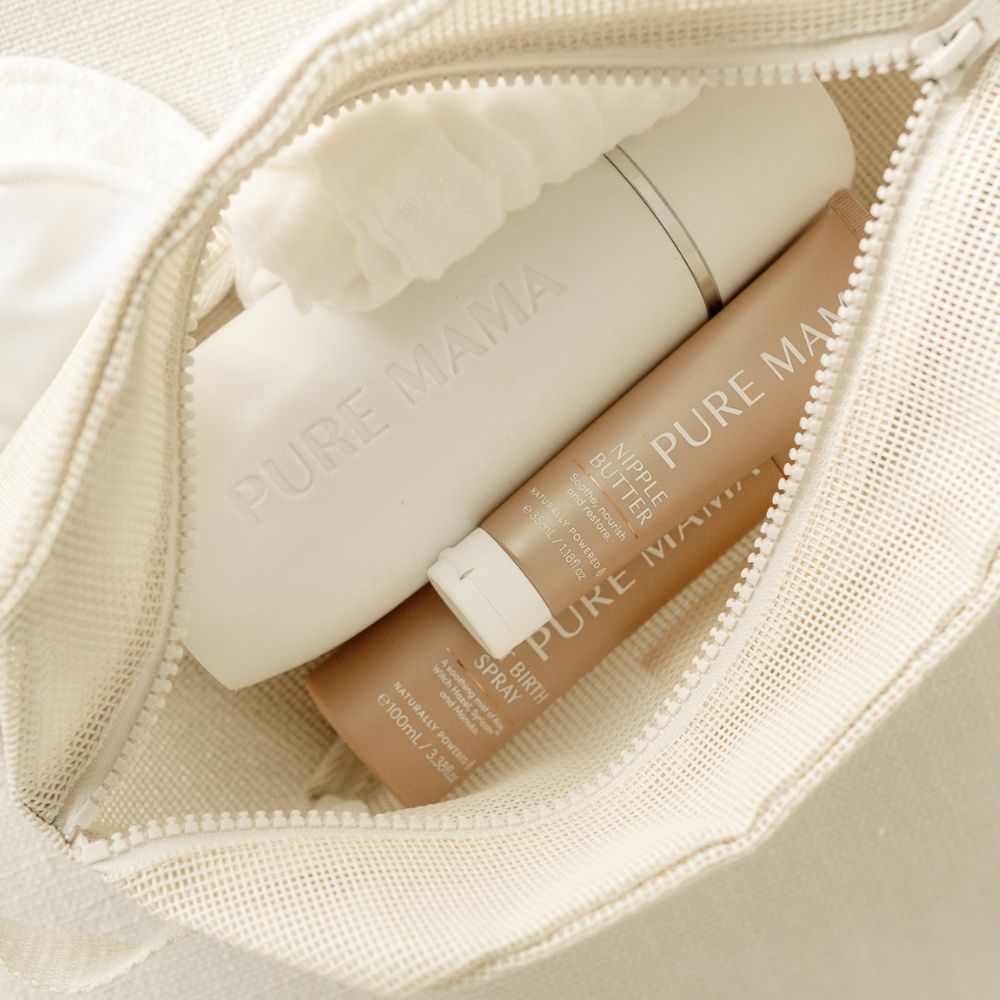 A beige zippered pouch from Pure Mama NZ holds their Birth & Postpartum Recovery Kit, featuring a white bottle and tan tube—ideal for new mothers—with soft fabric lining visible inside.