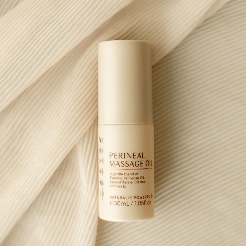 A beige 30mL bottle of Pure Mama NZ Perineal Massage Oil rests on cream fabric. Made with nourishing oils and vitamin E, it’s formulated to support skin elasticity and gentle birth preparation during pregnancy.