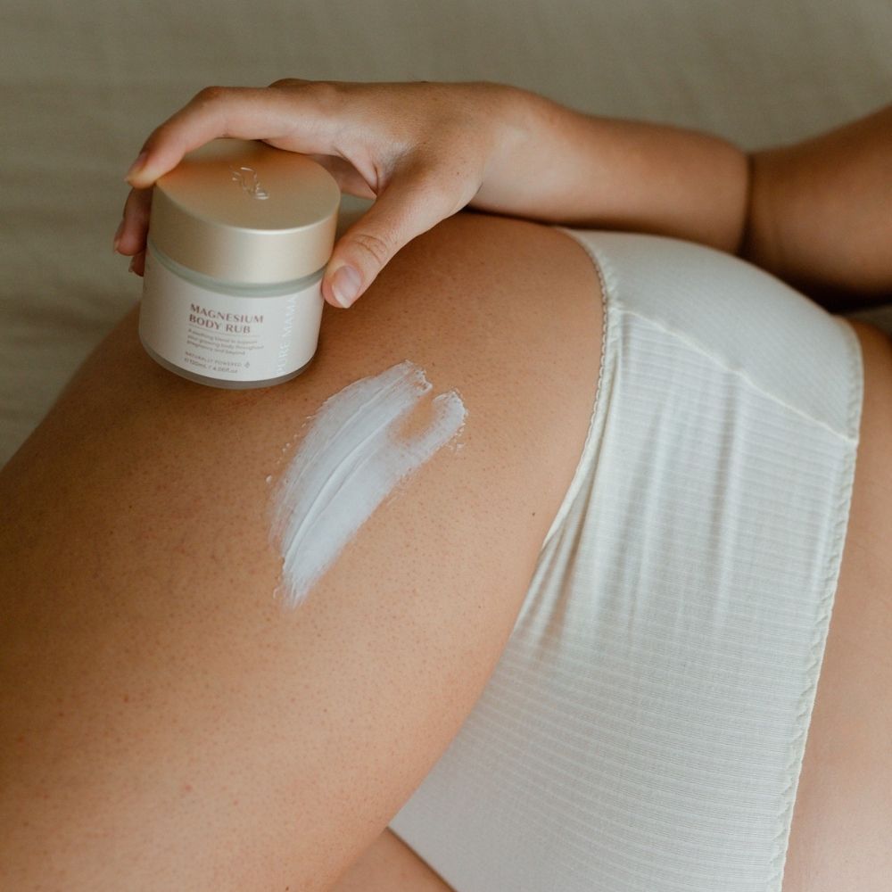 A person in white underwear applies Pure Mama NZ Magnesium Body Rub to their upper thigh, showcasing it as an ideal addition to the Pure Mama NZ Pregnancy Care Set.